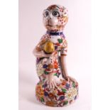 A ceramic figure of a crouching monkey decorated in the Imari palette,