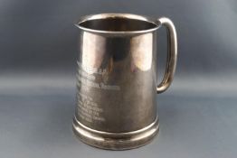 A silver mug with a thick glass bottom, with plain tubular 'C' form handle,