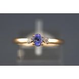 A yellow metal three stone tanzanite and diamond ring. Hallmarked 9ct gold, Birmingham. Size P