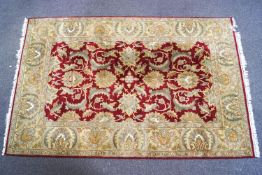 A large knotted wool Asian style carpet with a central claret field