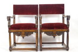 A pair of Spanish style arm chairs in carved hard wood with over stuffed rectangular back pads,