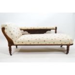An Edwardian chaise longue with a hardwood frame carved with floral motifs and ribbed panels and