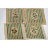 Four gros point needlework chair seat covers with floral medallions on a ground of green stripes,