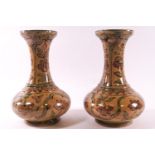 A pair of early 20th century Persian pottery vases, each decorated with flowers on a beige ground,