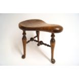 An unusual 19th century stool, with three legs on pad and ball feet linked by turned stretchers,