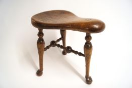 An unusual 19th century stool, with three legs on pad and ball feet linked by turned stretchers,