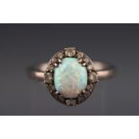 A white metal cluster ring set with synthetic opal cabochon and cubic zirconias.