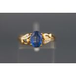A yellow metal dress ring set with an oval sapphire