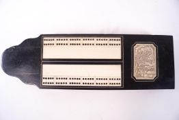 A late 19th century ebony cribbage board inset with a Chinese carved panel,
