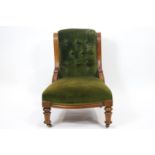An Edwardian mahogany button back armchair with carved curved side rails above an over stuffed seat