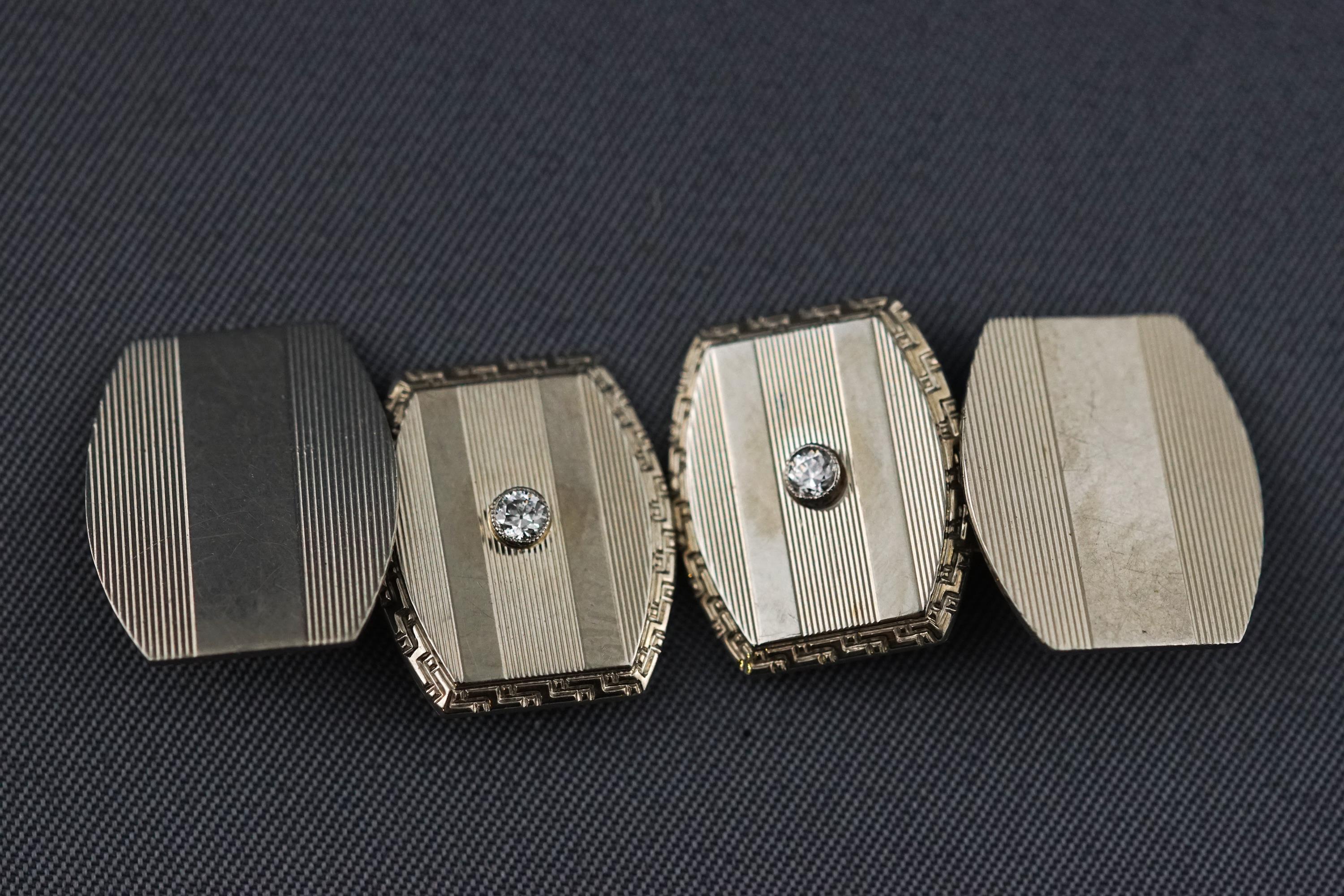 A white metal pair of chain link cufflinks each set with a round brilliant cut diamond