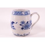 An 18th century English blue and white decorated barrel form mug with turned bands and sprigs of