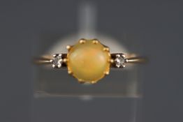 A yellow metal three stone ring set with a cabochon cut opal and two diamonds.