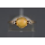 A yellow metal three stone ring set with a cabochon cut opal and two diamonds.