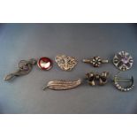 A collection of eight white metal brooches of variable designs.