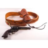 A tan leather holster belt with tooled decoration set with a replica colt single action army 45 gun