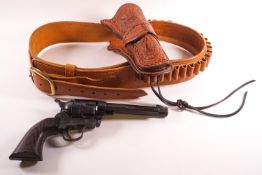 A tan leather holster belt with tooled decoration set with a replica colt single action army 45 gun