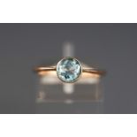 A yellow metal single stone ring set with a round faceted cut aquamarine. Stamped 9c for 9ct gold.