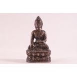 A small bronze figure of a buddah meditating whilst sat in the lotus position,