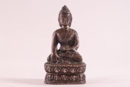 A small bronze figure of a buddah meditating whilst sat in the lotus position,