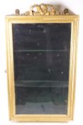 A gilded wall display cabinet of rectangular form set with a plain glazed door