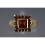 A yellow metal square cluster ring set with almandine garnets.