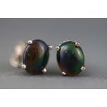 A white metal pair of single stone studs each set with a cabochon Ethiopian opal.