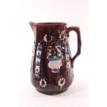 A Victorian barge ware jug with polychrome decorated cameo floral panels on a brown ground