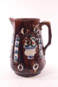 A Victorian barge ware jug with polychrome decorated cameo floral panels on a brown ground