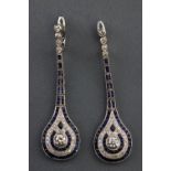 A white metal pair of drop earrings. Each set with a round brilliant cut diamond