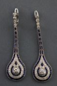 A white metal pair of drop earrings. Each set with a round brilliant cut diamond