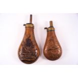 Two 19th century copper powder flasks, both embossed, one with a cannon and flasks,