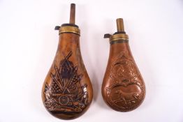 Two 19th century copper powder flasks, both embossed, one with a cannon and flasks,