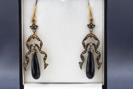 A yellow and white metal pair of drop earrings each having an elongated faceted teardrop jet....