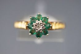 A yellow and white metal cluster ring set with emeralds and central diamond.