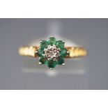 A yellow and white metal cluster ring set with emeralds and central diamond.