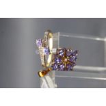 A yellow metal ring set with two tanzanites and diamond shoulders,