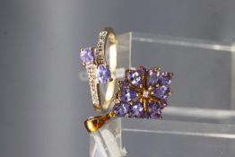 A yellow metal ring set with two tanzanites and diamond shoulders,