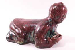 A flambe and turquoise glazed terracotta Chinese head sleeping block in the form of a crouching man