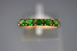 A yellow metal half hoop ring set with five oval faceted cut peridot (untested) Size: N