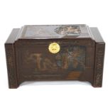 An Asian camphur hardwood chest of rectangular form carved with panels of figures in a garden and