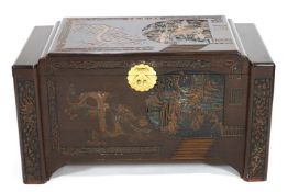 An Asian camphur hardwood chest of rectangular form carved with panels of figures in a garden and