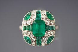 A white metal dress ring. Having a central rectangular cut emerald of approximately 1.60cts.