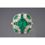 A white metal dress ring. Having a central rectangular cut emerald of approximately 1.60cts.
