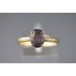 A yellow metal dress ring set with a low commercial quality amethyst and diamond shoulders.