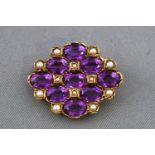 A yellow metal brooch set with amethyst and seed pearls. Pin and revolver fitting.