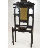 A Victorian carved oak coat stand with mirror above a hinged box on turned legs,