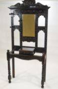 A Victorian carved oak coat stand with mirror above a hinged box on turned legs,