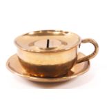 A brass novelty money box in the form of a tea cup,