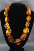 A single strand of large abstract amber beads with base metal hook clasp.